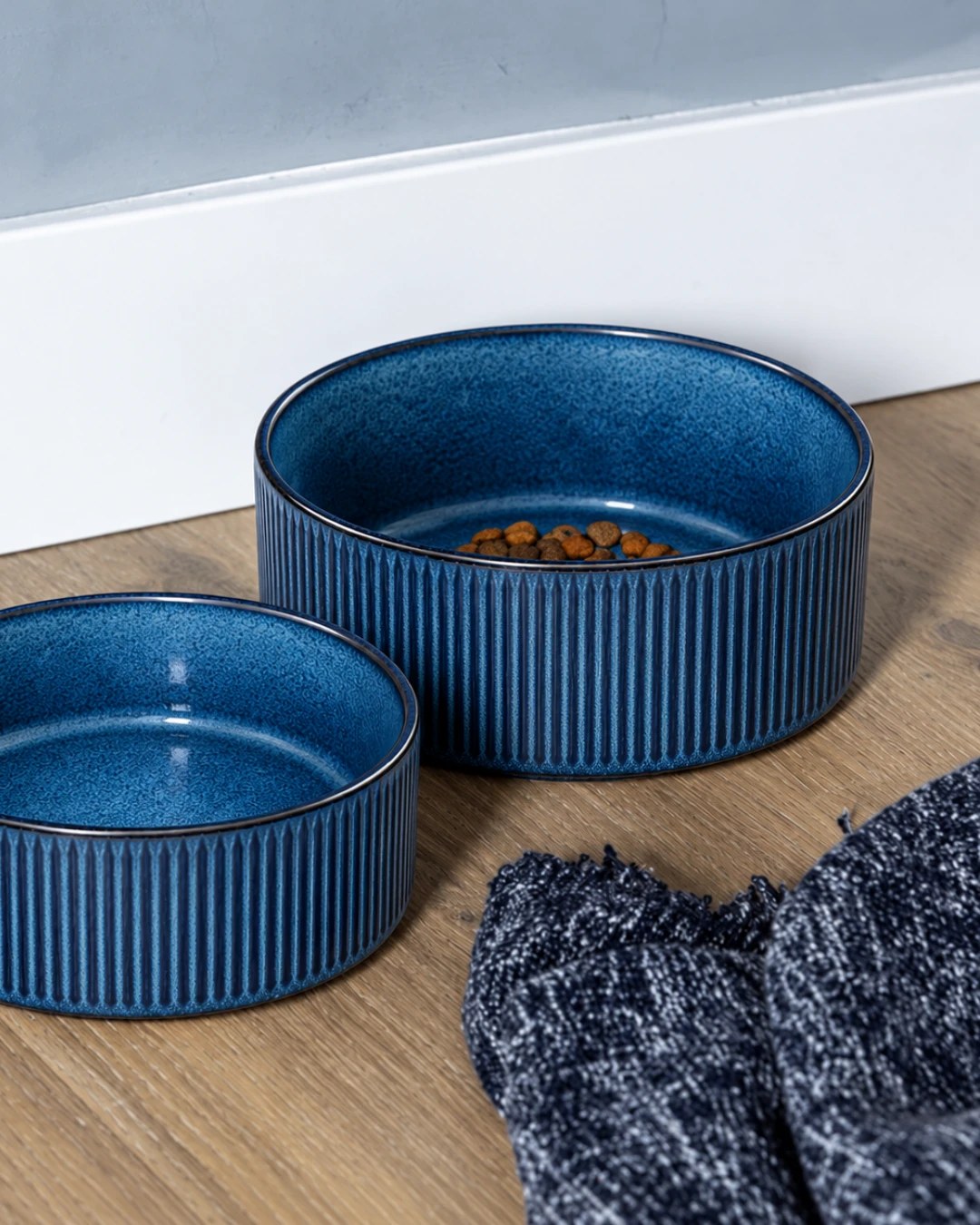 Two blue ceramic dog bowls, one filled with kibble