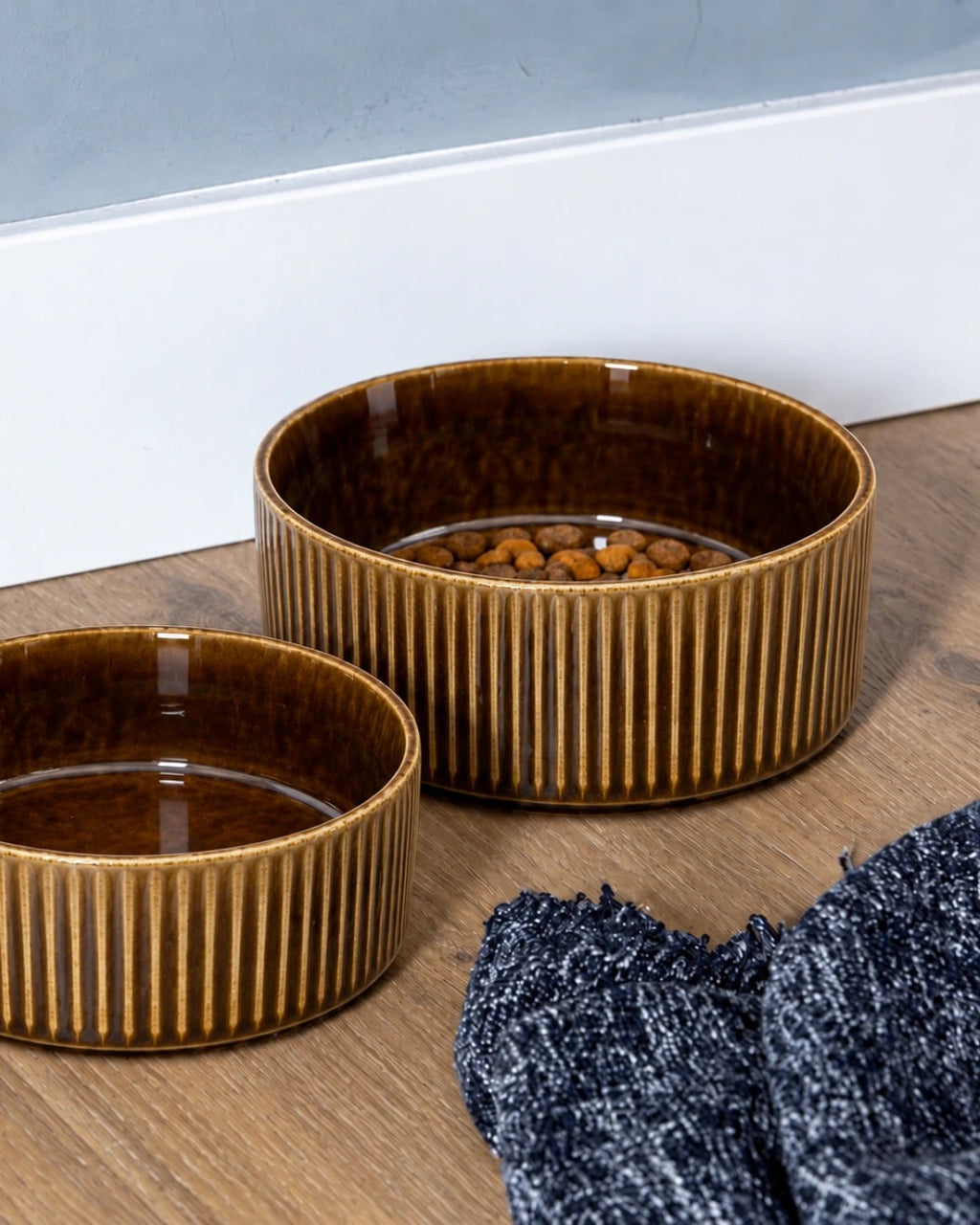 Two brown ceramic dog bowls, one filled with kibble