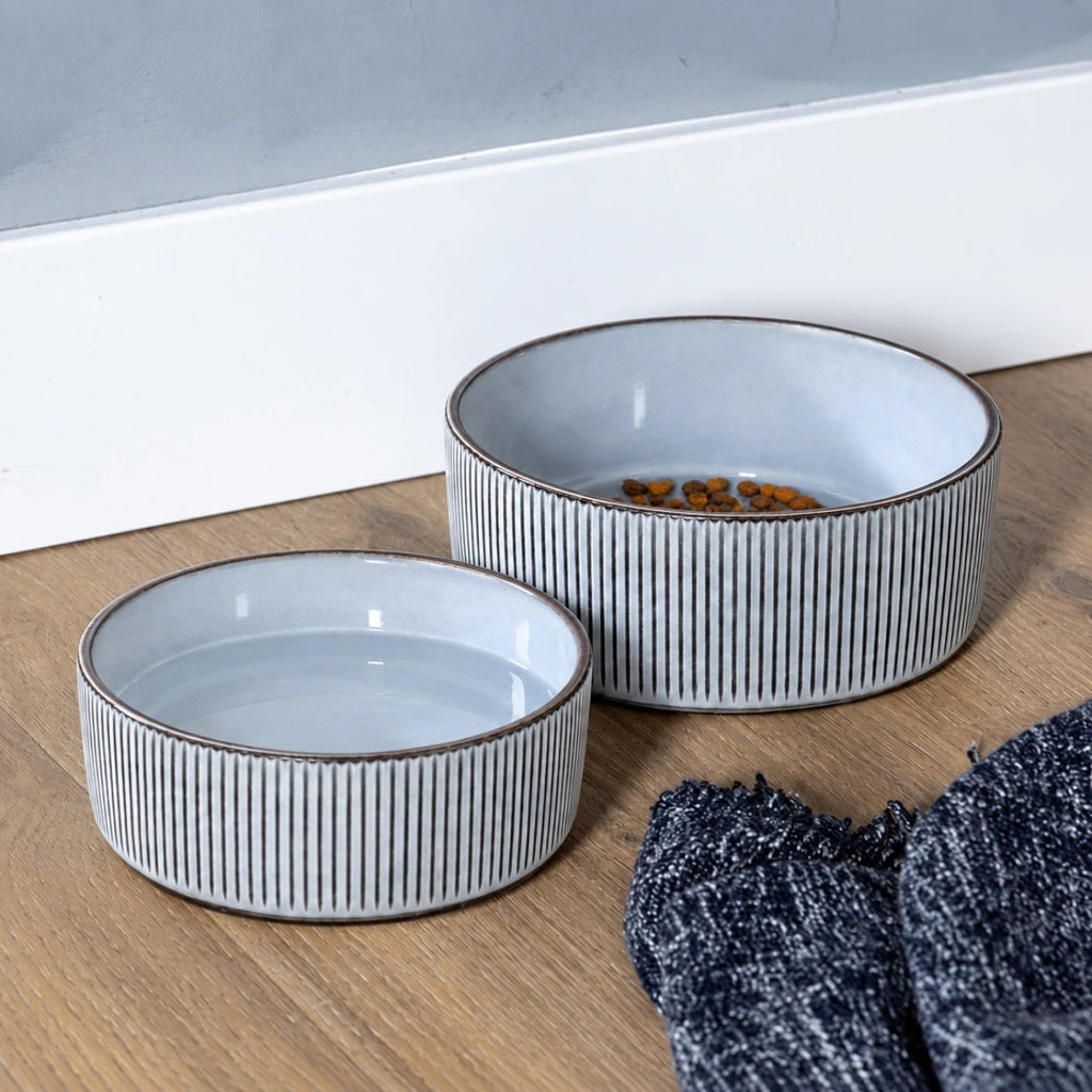 Two grey ceramic dog bowls, one filled with kibble