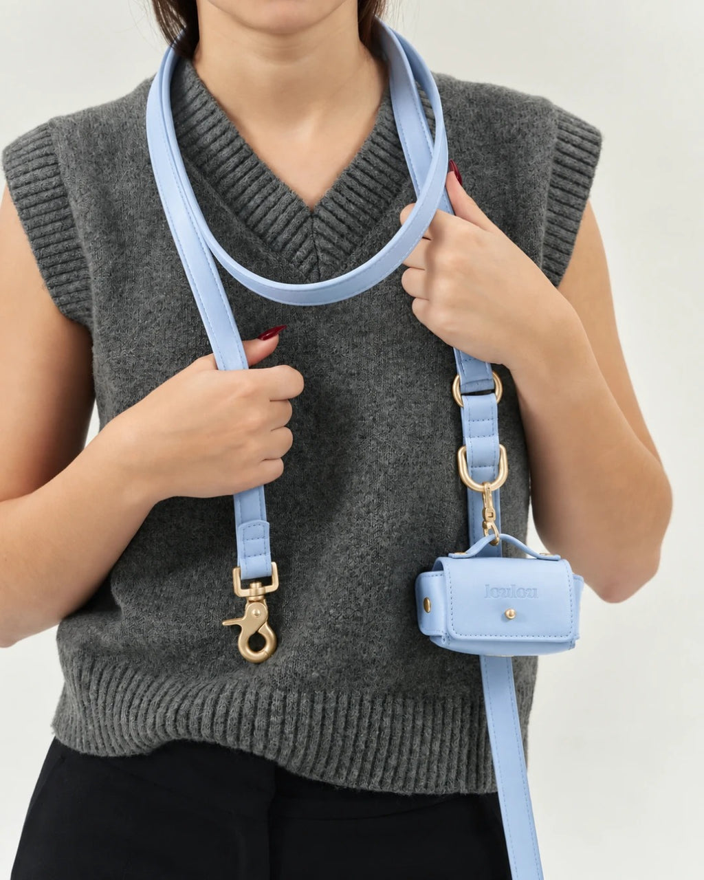 Sky blue pouch clipped to the leash, worn over a grey knit vest