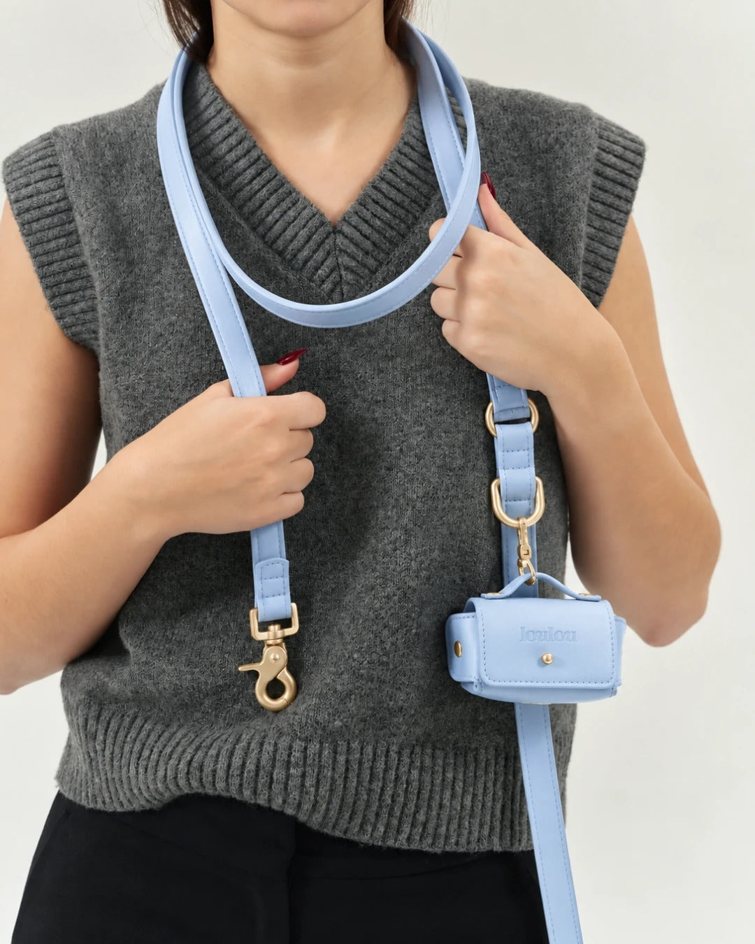 Sky blue pouch clipped to the leash, worn over a grey knit vest