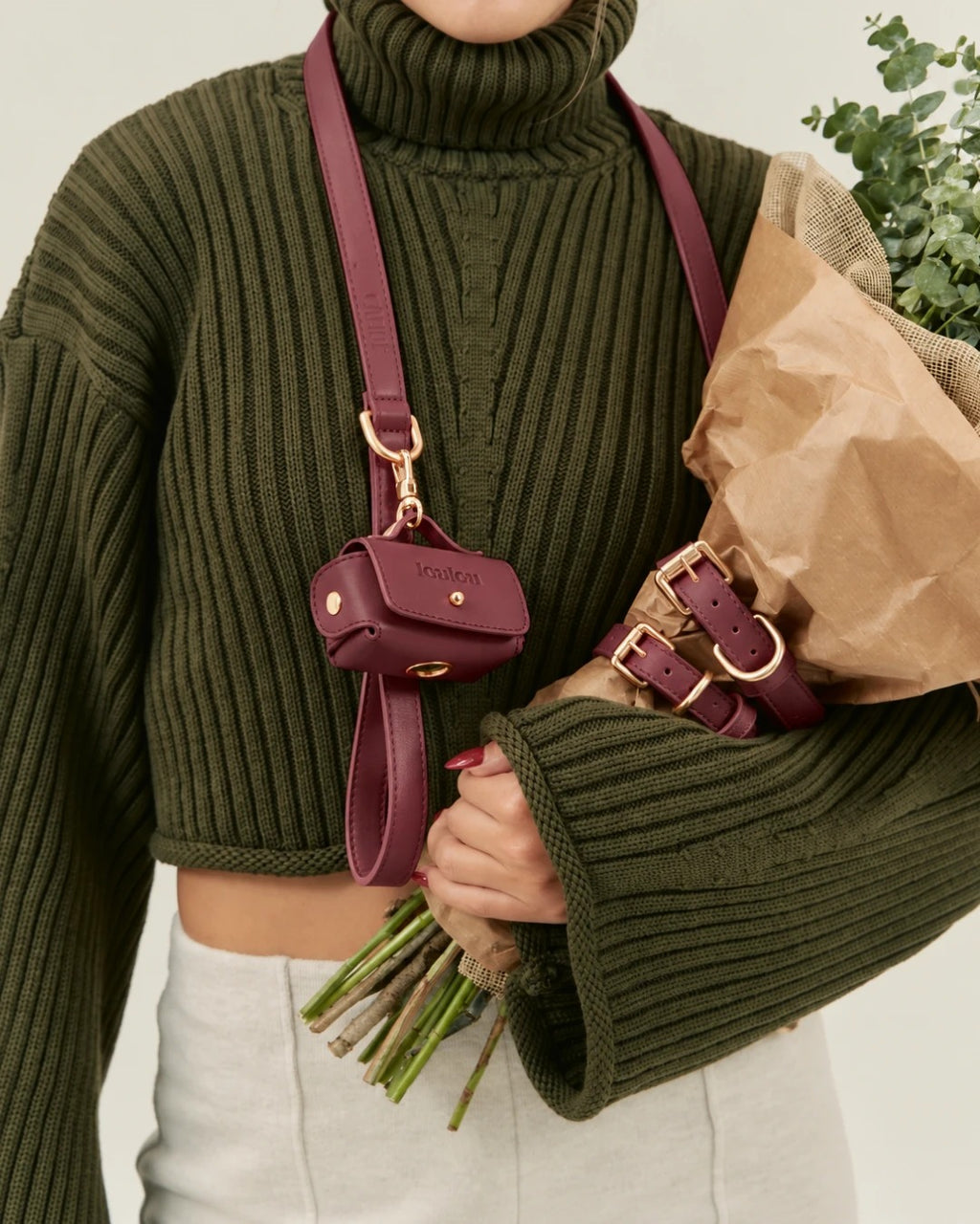 Burgundy pouch clipped to the leash, worn across the body over a green jumper