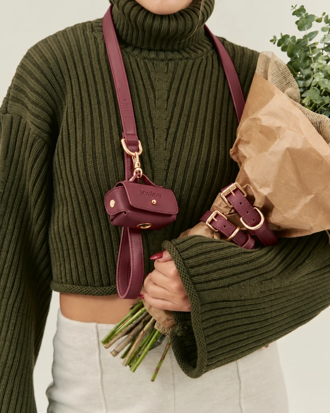 Burgundy pouch clipped to the leash, worn across the body over a green jumper