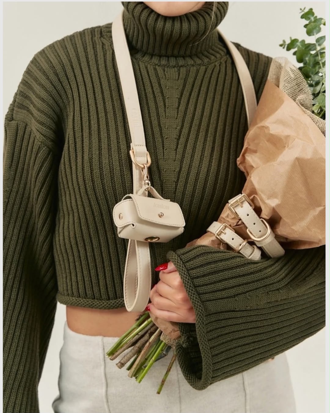 Cream pouch worn across the body over a green jumper