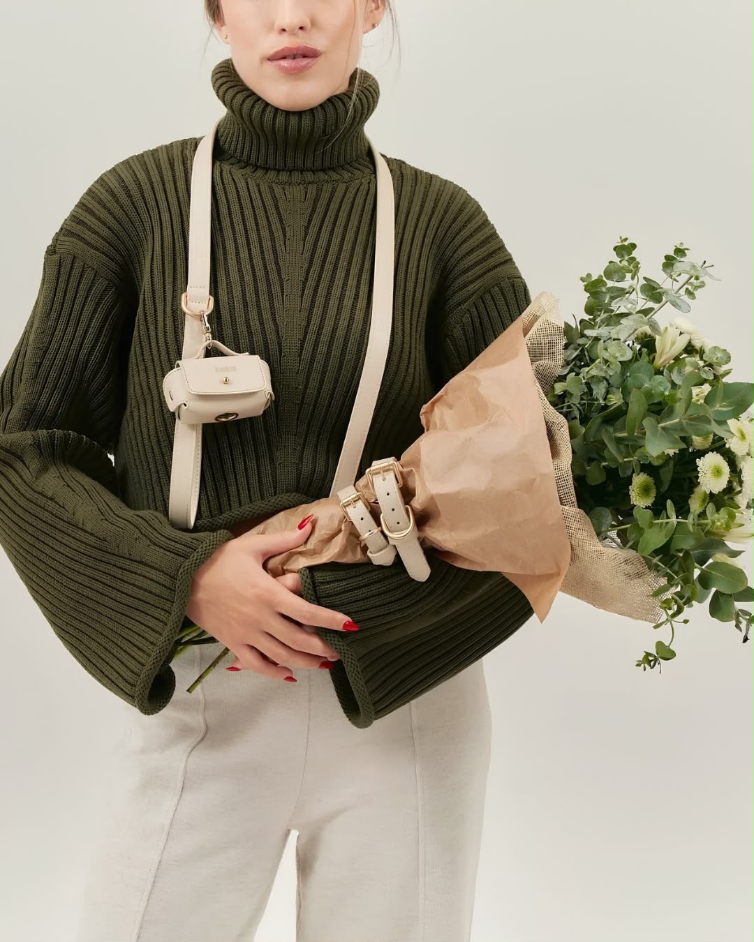 Cream pouch on its strap, with a bouquet of flowers